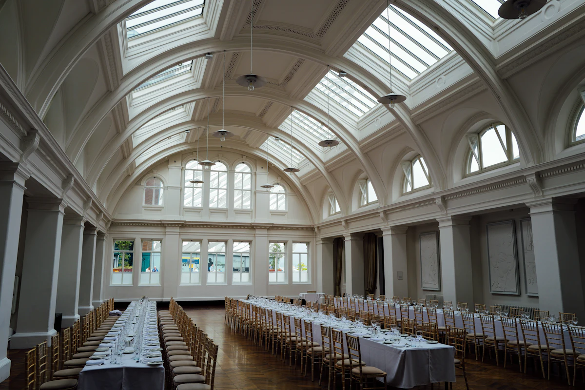 Lange gedekte tafels in een lichte zaal, klaar voor een bruiloft