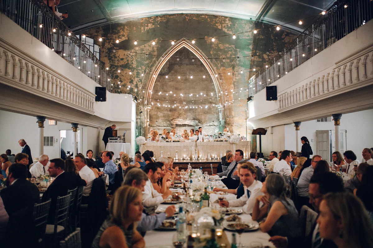 Volle zaal met gasten aan lange tafels tijdens een feest